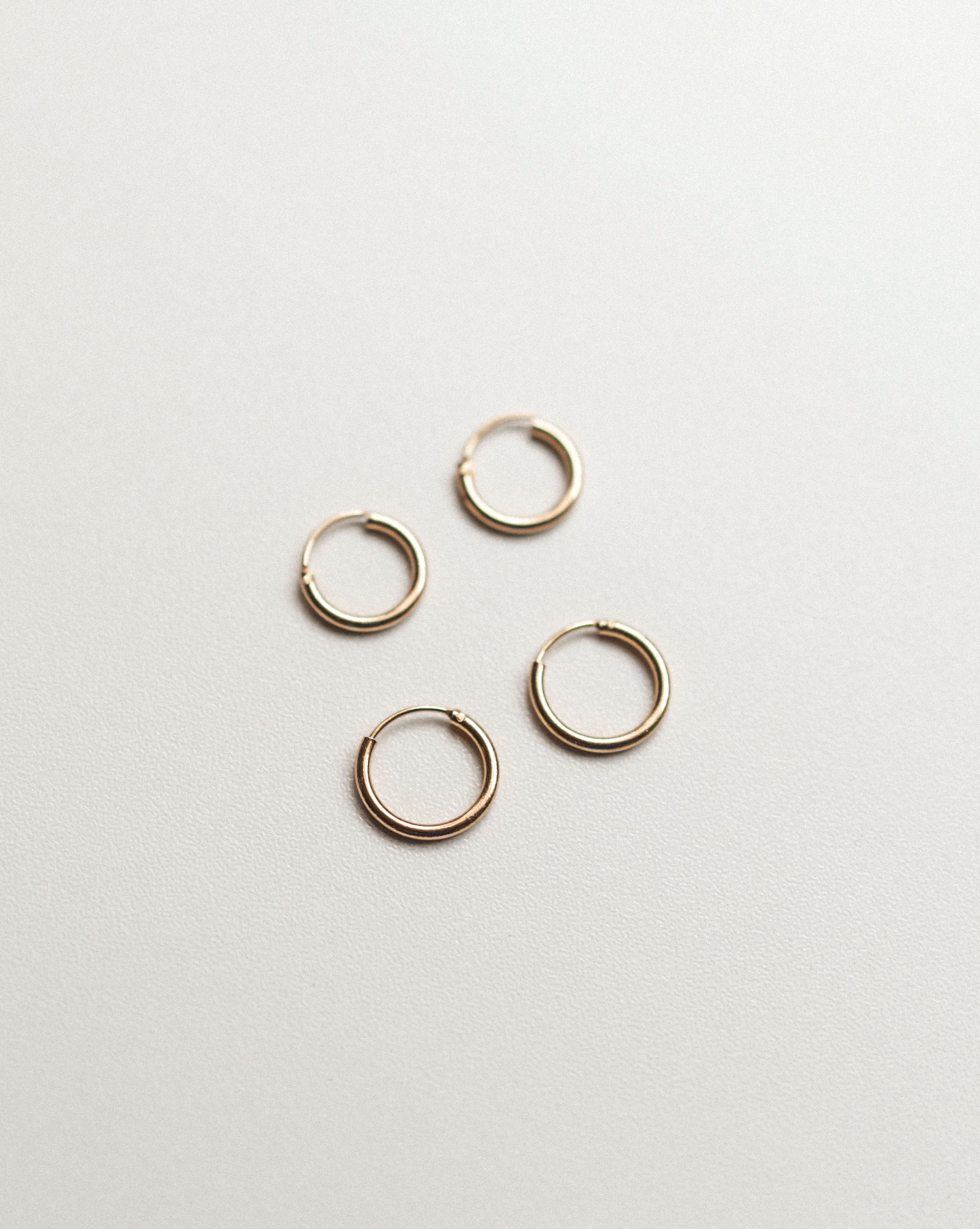 Set of gold hoop earrings on a light gray background