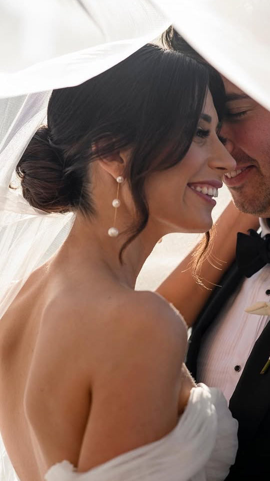 Wedding couple sharing a tender moment under an umbrella.