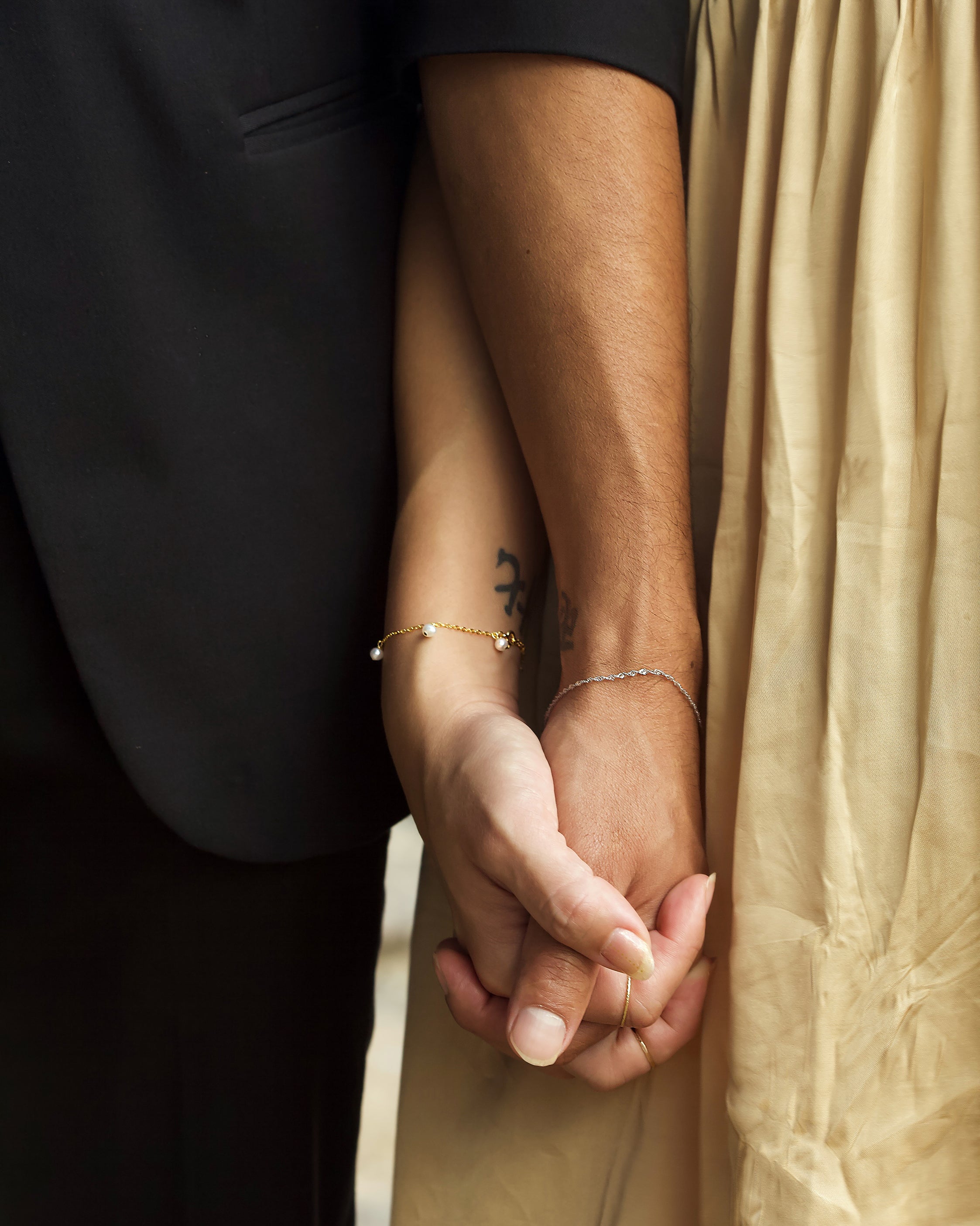 A man and a woman holding hands wearing couples bracelets