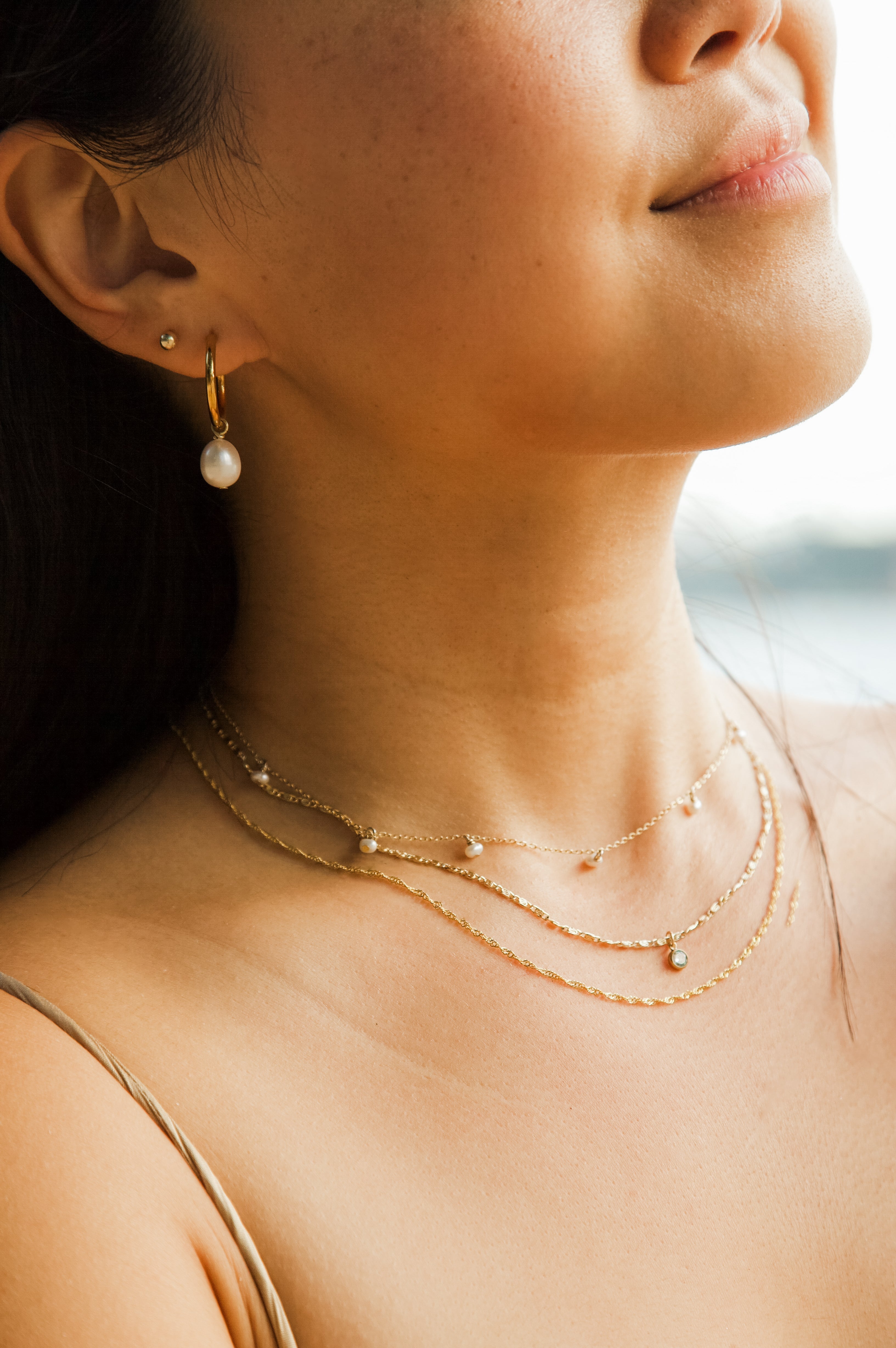 Close-up of a woman wearing a delicate necklace and earring set with a blurred background