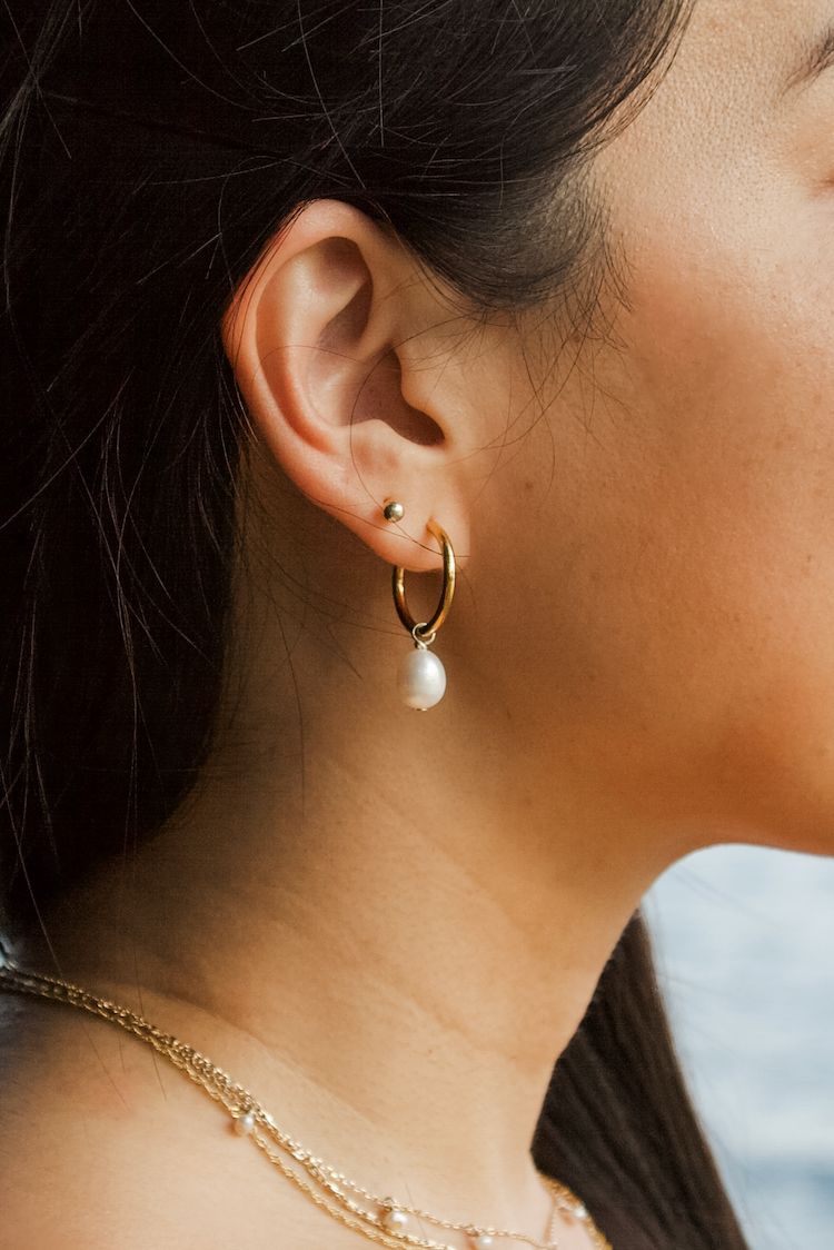 Woman wearing gold hoop earrings with a blurred background
