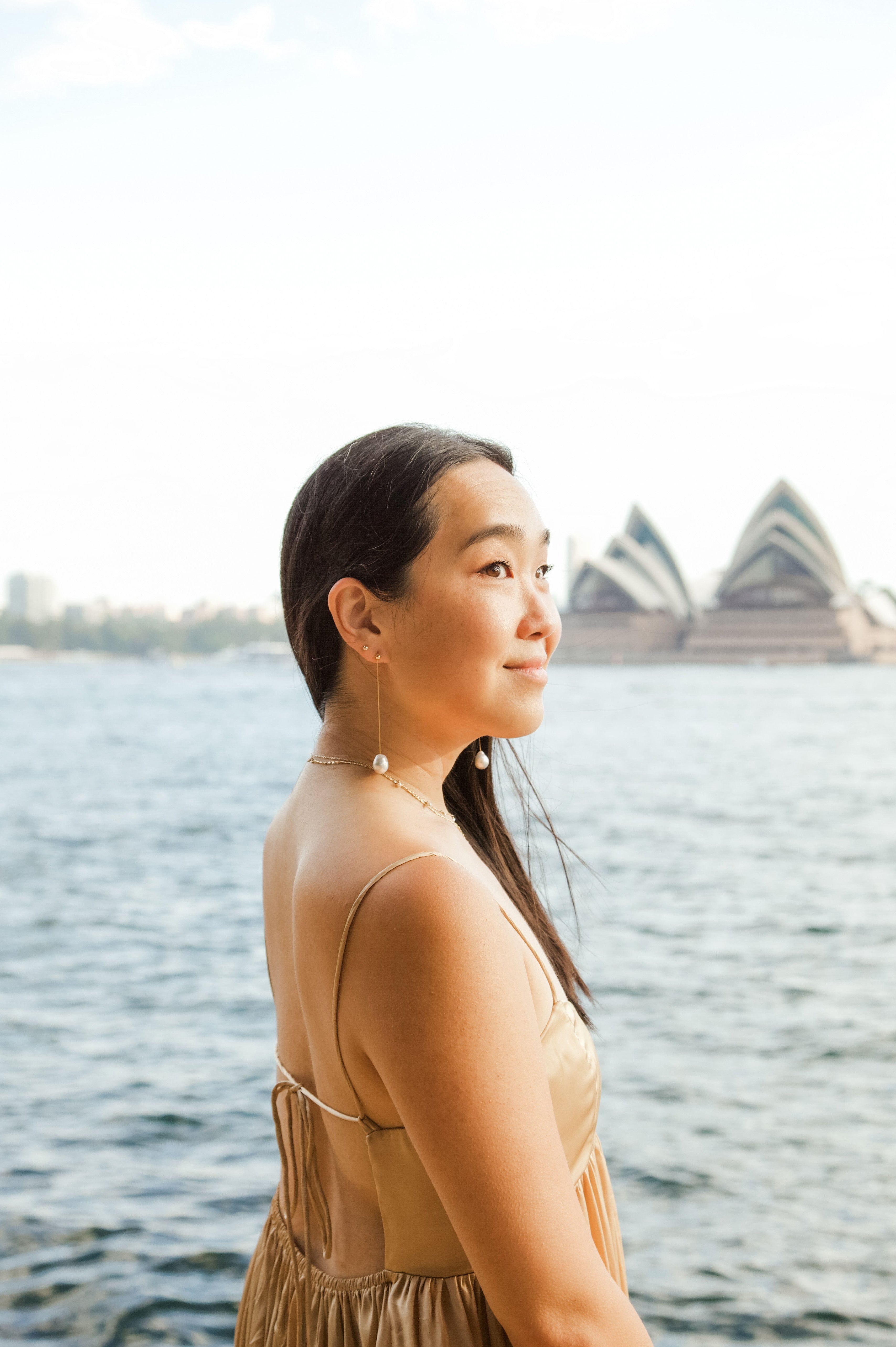 Woman standing by a waterfront with the Sydney Opera House in the background